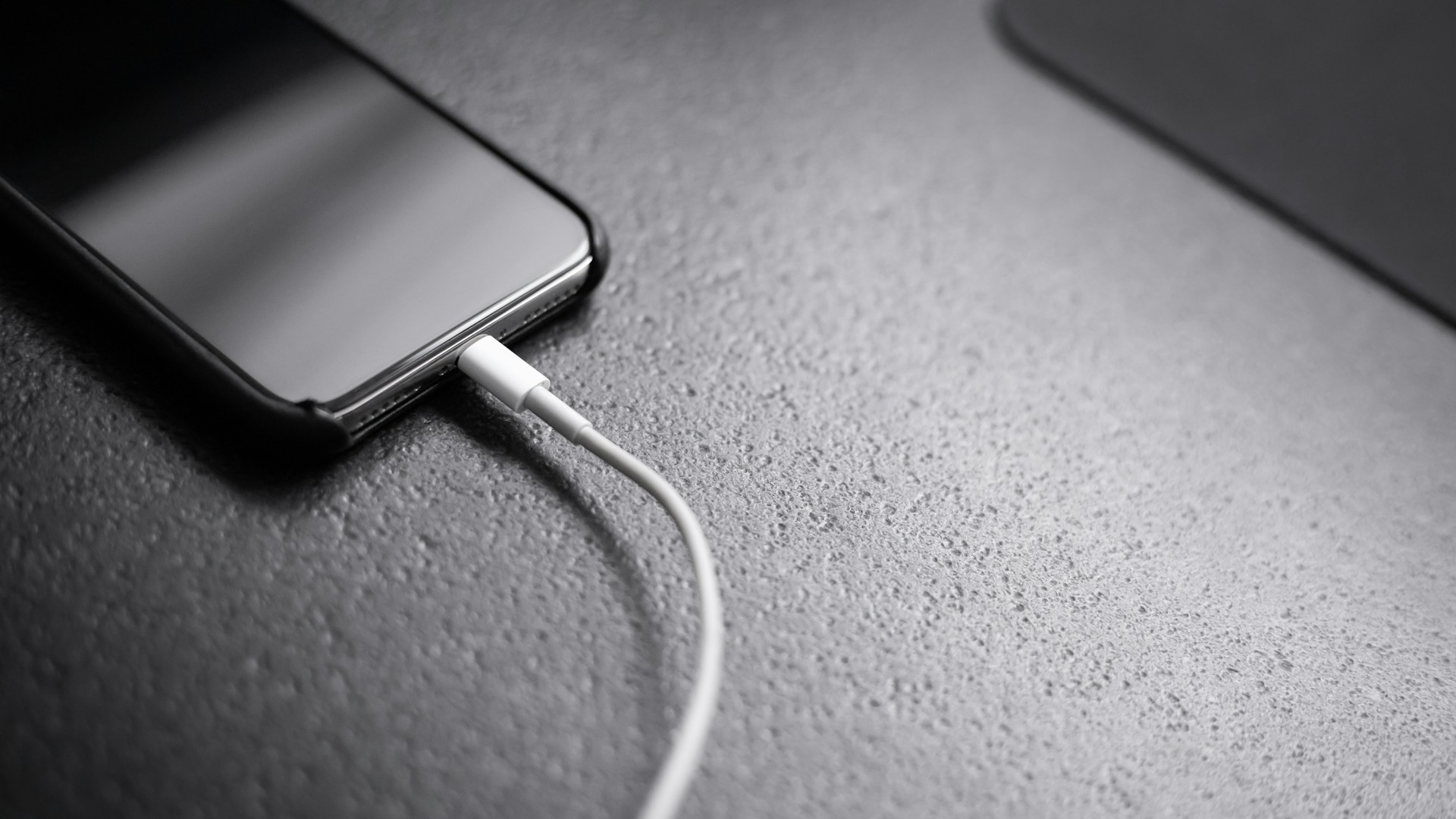 black smartphone with charger cord connected