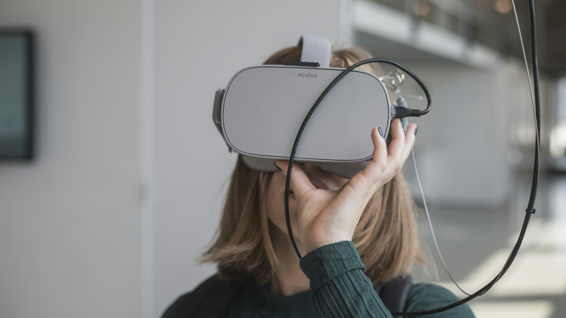 woman in black sweater holding white and black vr goggles