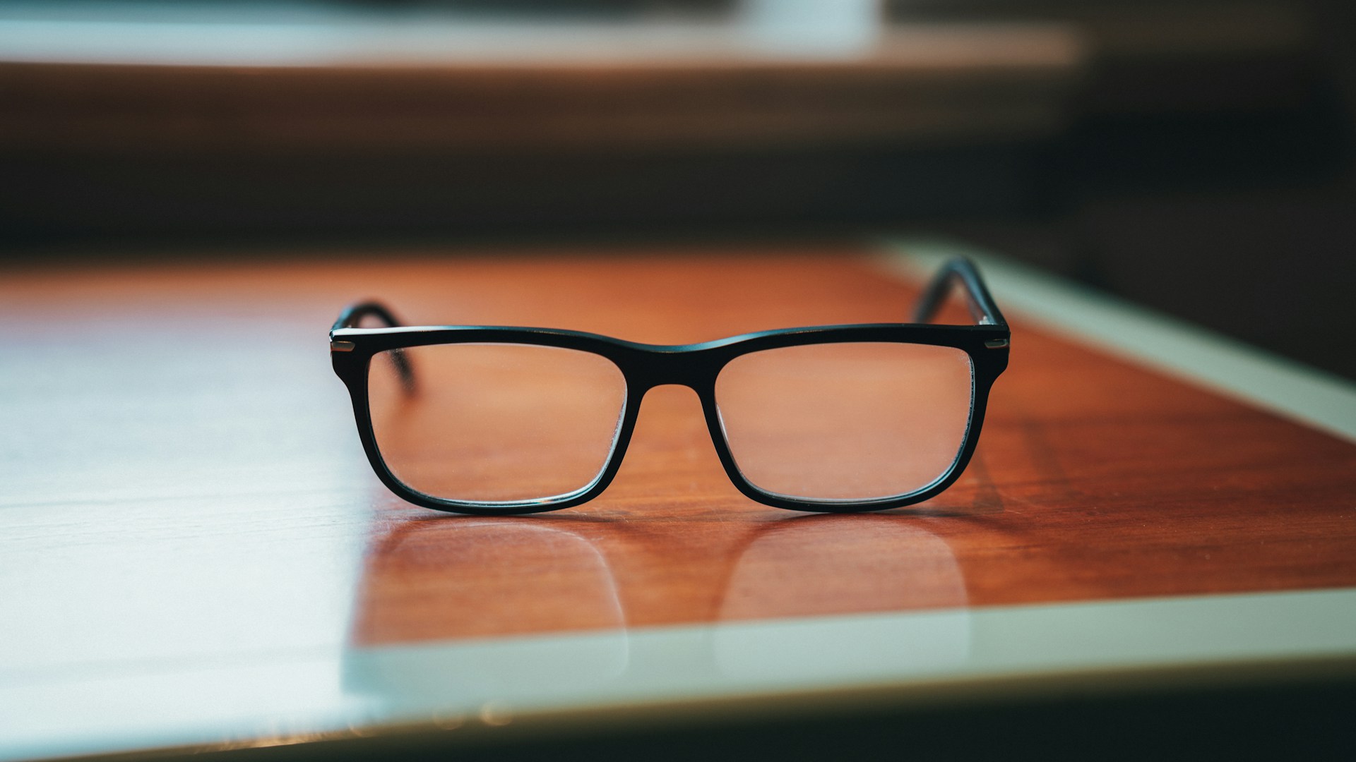 a pair of black glasses on a wooden surface