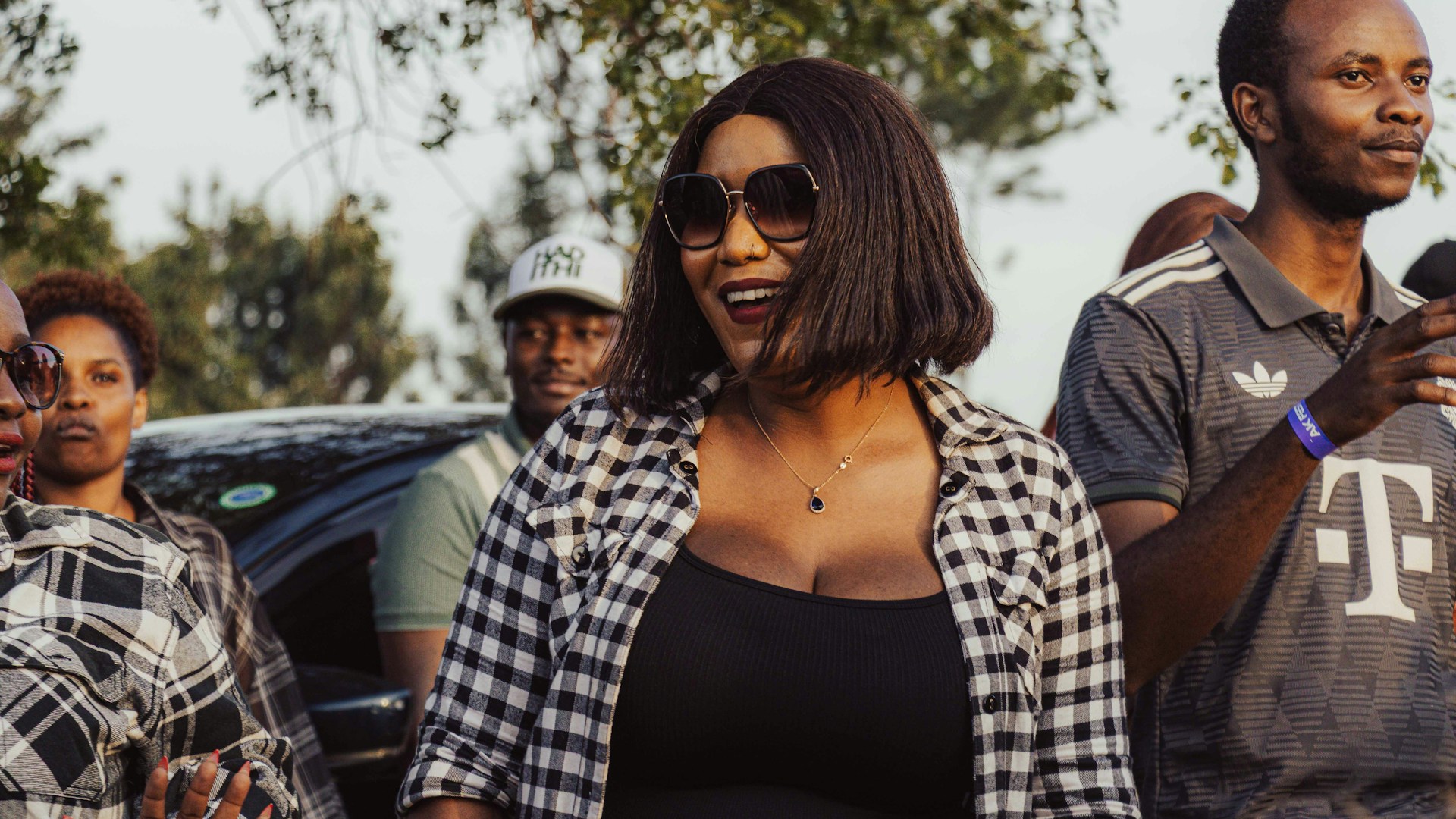 A woman in sunglasses and plaid shirt smiles.