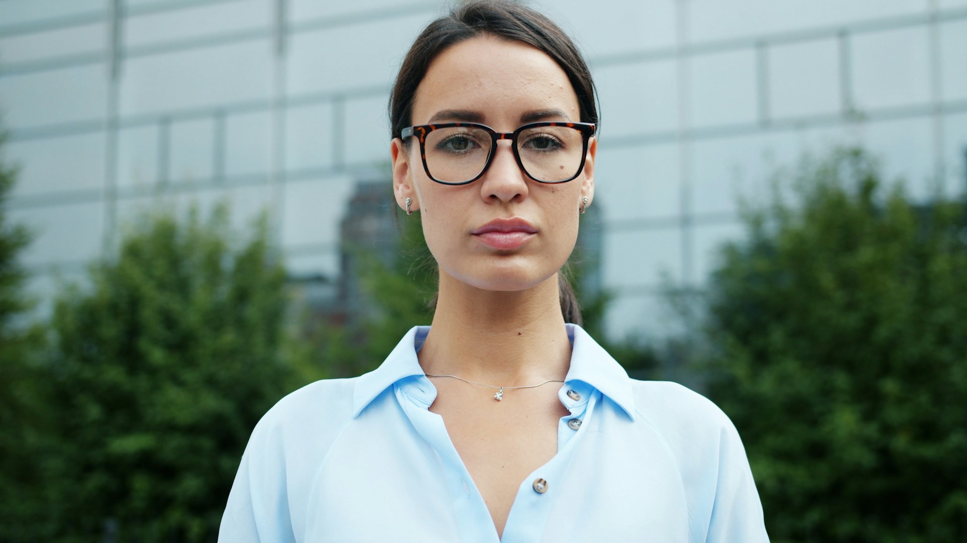 Young woman wearing glasses and blue shirt outdoors