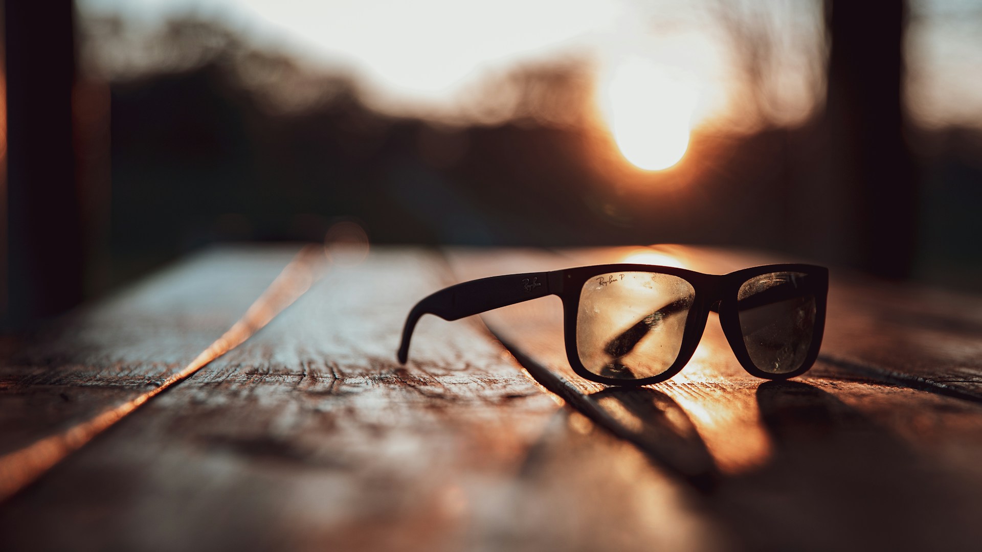 selective focus photography of black sunglasses on brown surface